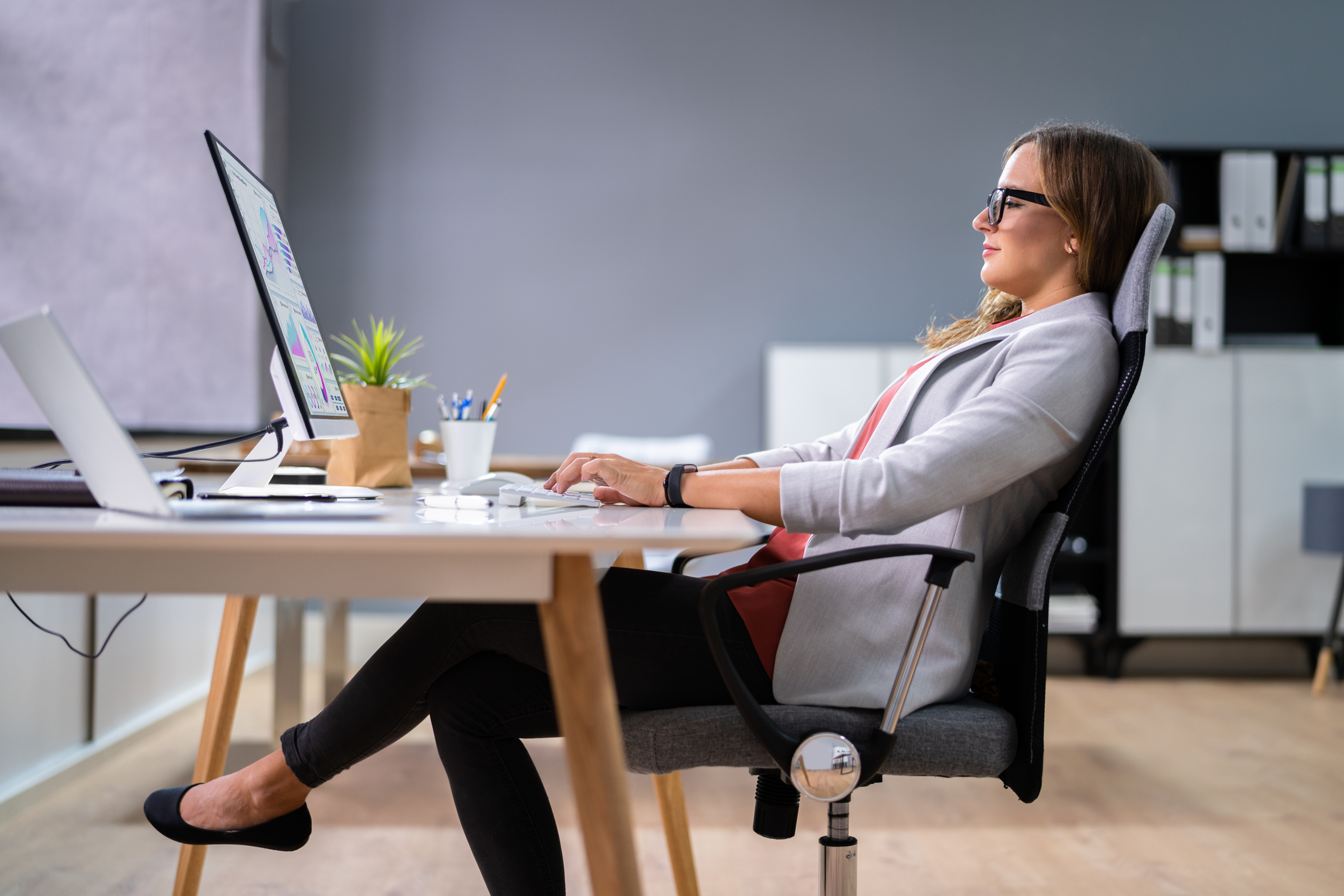 Person sitting upright at a desk with relaxed shoulders and a tall spine, taking a short movement pause